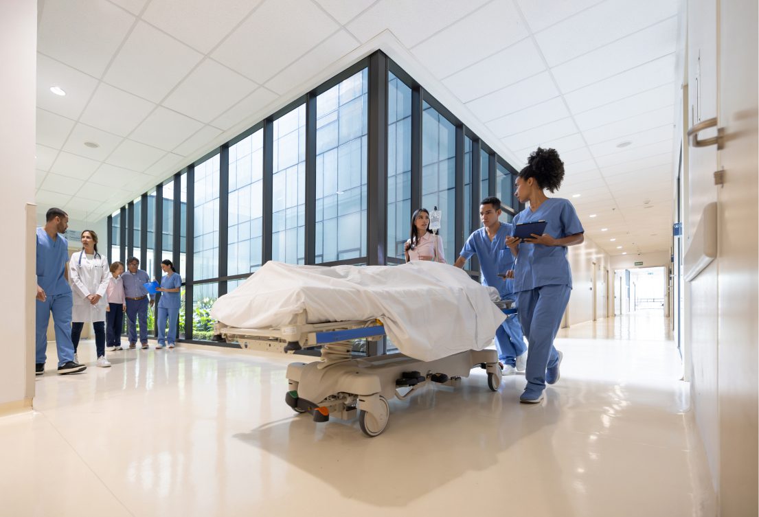 Medical team moving patient on hospital gurney.